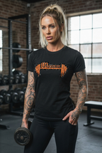 Woman in a gym wearing a black t-shirt with orange BD Athletic Dept logo, holding a dumbbell.