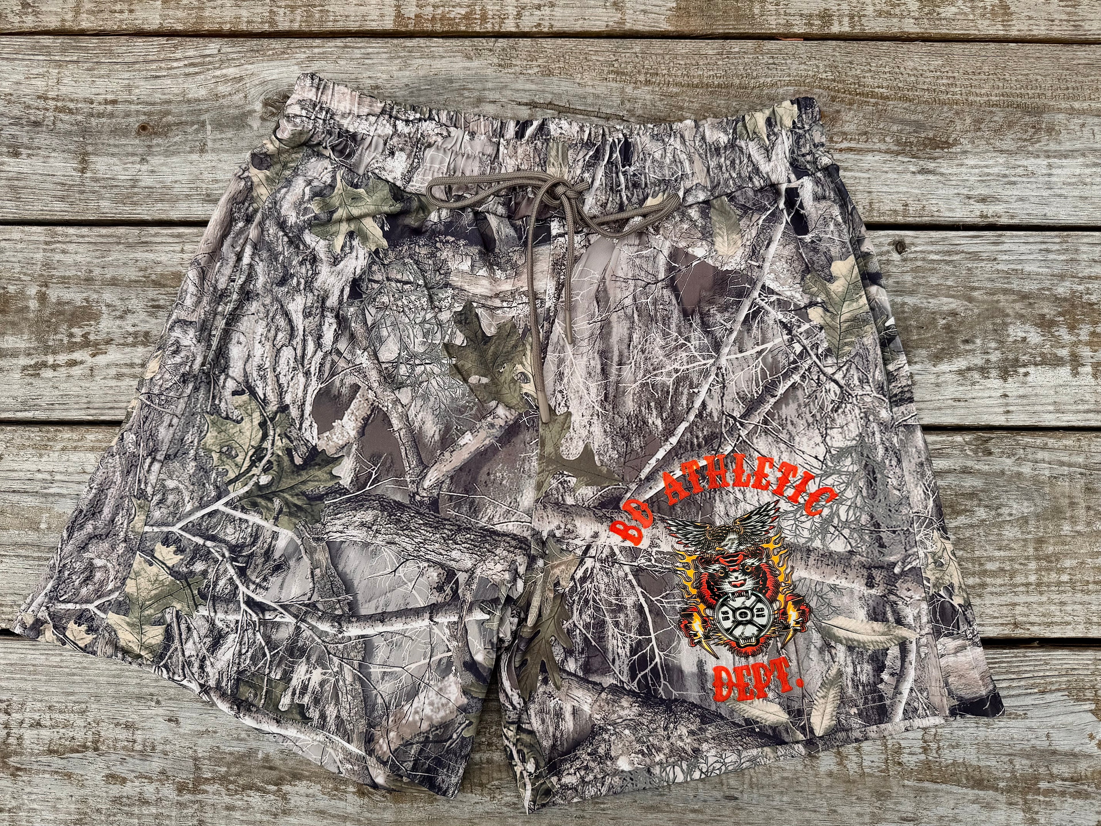 Camouflage shorts with BD Athletic Dept text and logo on a wooden surface