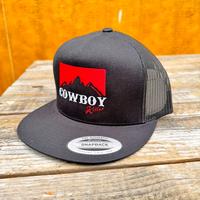 Black trucker snapback hat with a red graphic and 'Cowboy killer' text on a wooden surface.