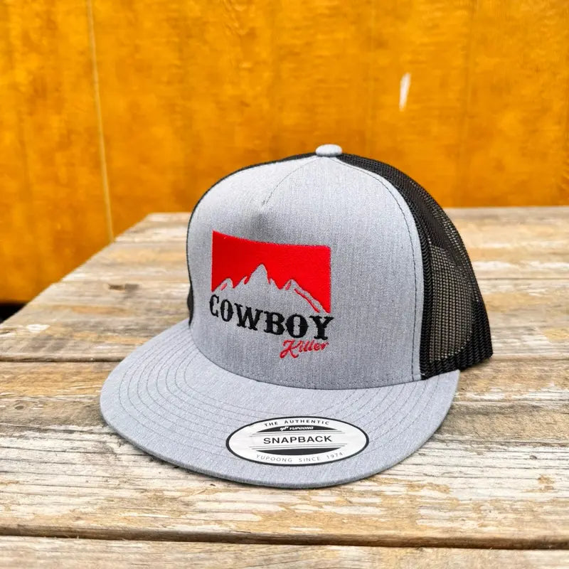 heather grey and black trucker snapback hat with red logo and "cowboy killer" text on a wooden surface