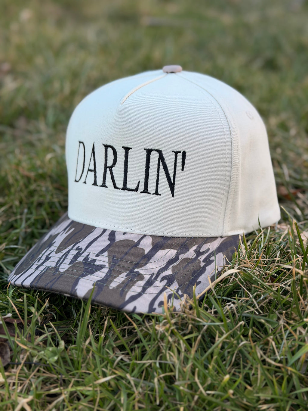 Beige and camo snapback hat with 'Darlin' on a grassy background