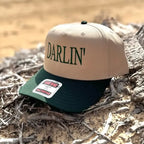 Tan and green snapback hat with 'DARLIN'' text on a natural background