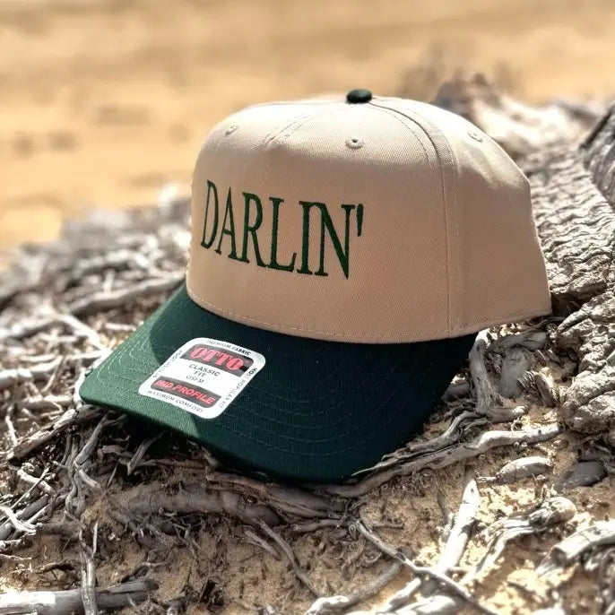 Tan and green snapback hat with 'DARLIN'' text on a natural background