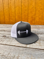 Black and white snapback hat with a barbell design on a wooden surface