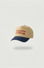 Beige and blue snapback hat with 'Expensive and Difficult' text on a white background