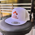 White snapback hat with orange 'i'm your huckleberry' text on a chair