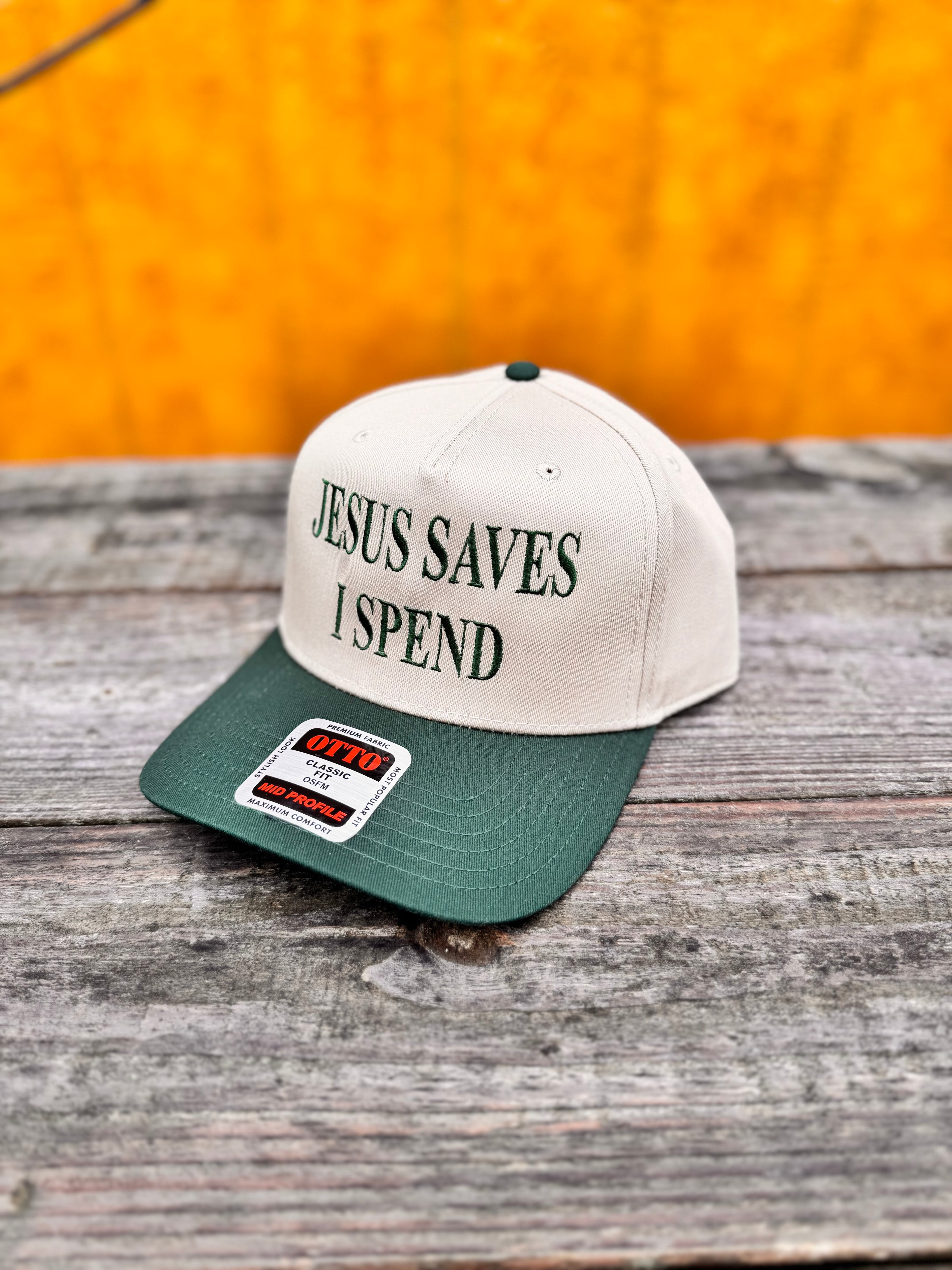 two tone beige and green snapchat hat with matching green  'Jesus Saves I Spend' text on a wooden surface
