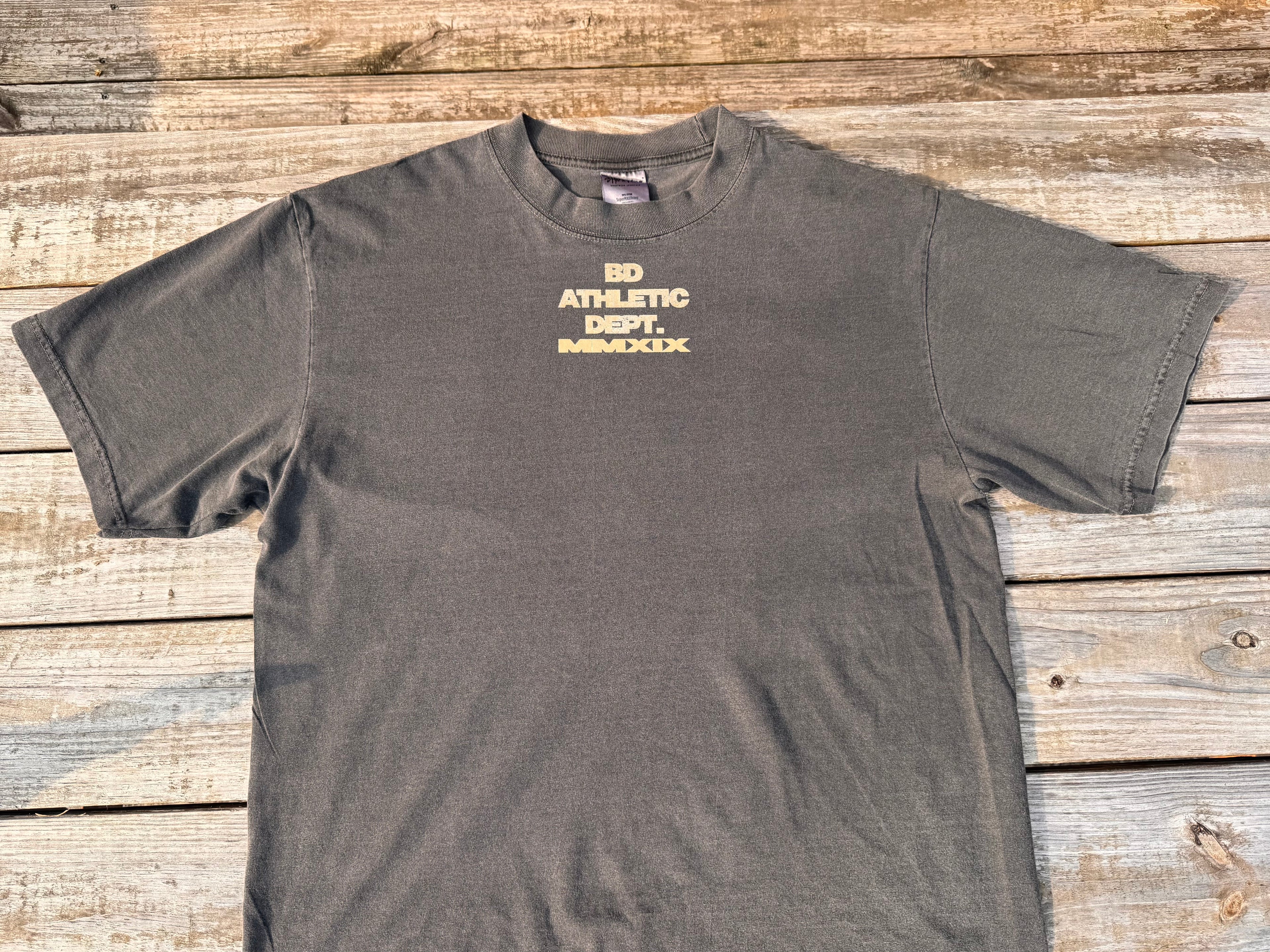 gray t-shirt with tan 'BD ATHLETIC DEPT.' text on a wooden table