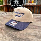 Beige and navy cap with text on a wooden surface, brand label visible