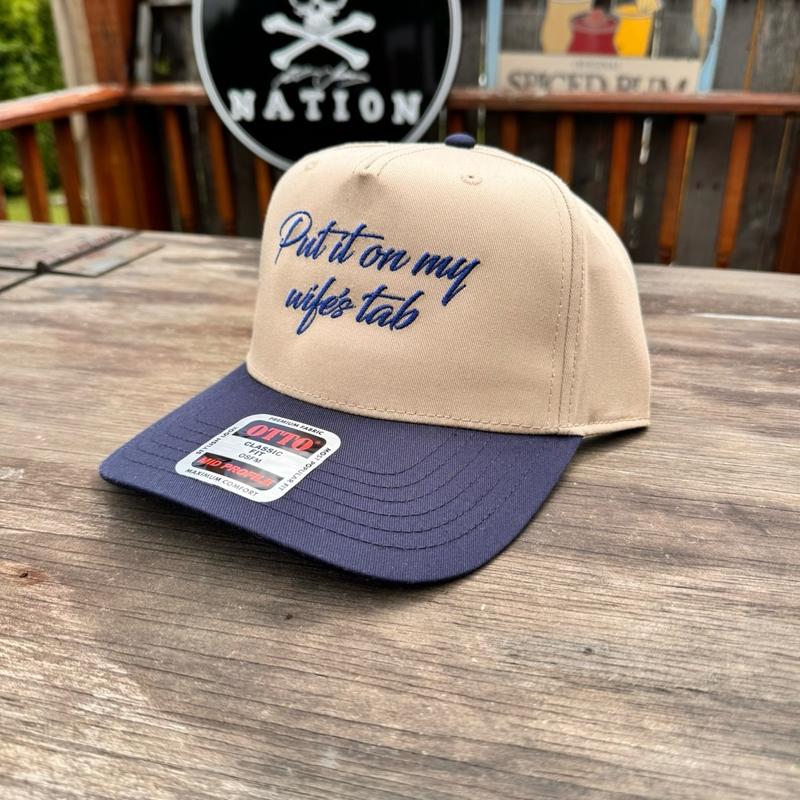 Beige and navy cap with text on a wooden surface, brand label visible