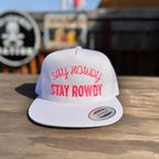 White snapback hat with red text 'Stay Howdy Stay Rowdy' on a wooden surface