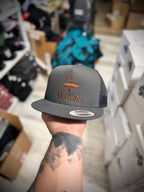 gray snapback hat with orange 'SAY WHEN' text held by a person in a store setting
