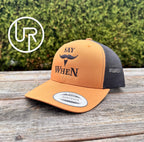 orange and black snapback hat with black 'SAY WHEN' text on a wooden table