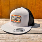 Silver and black snapback hat with 'Small D*ck Big Dreams' patch on a wooden surface.