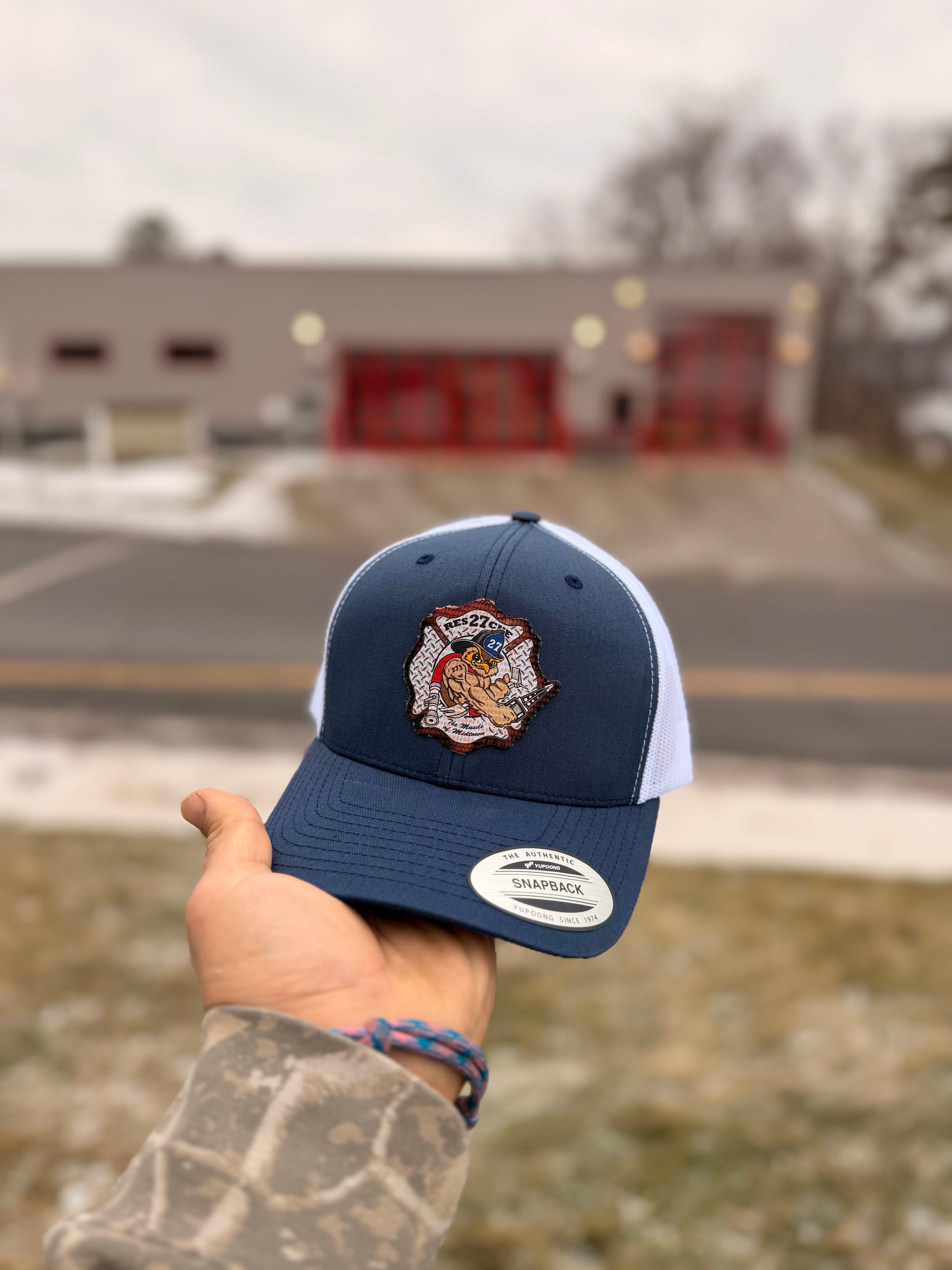 Navy blue cap with a logo held by a hand against a blurred background