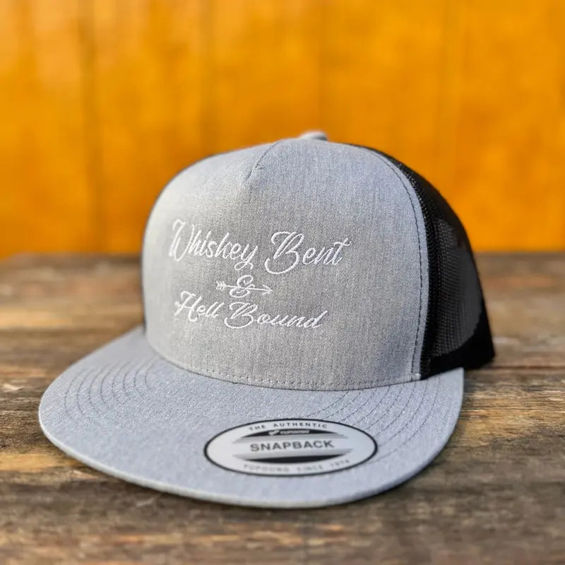 heather grey and black trucker snapback hat with 'Whiskey Bent & Hell Bound' text on a wooden surface.