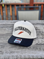 beige and navy snapback hat with black 'Y’ALLTERNATIVE' text on a wooden table