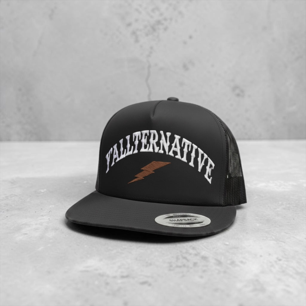 Black snapback hat with 'YALLTERNATIVE' text and lightning bolt on a countertop background