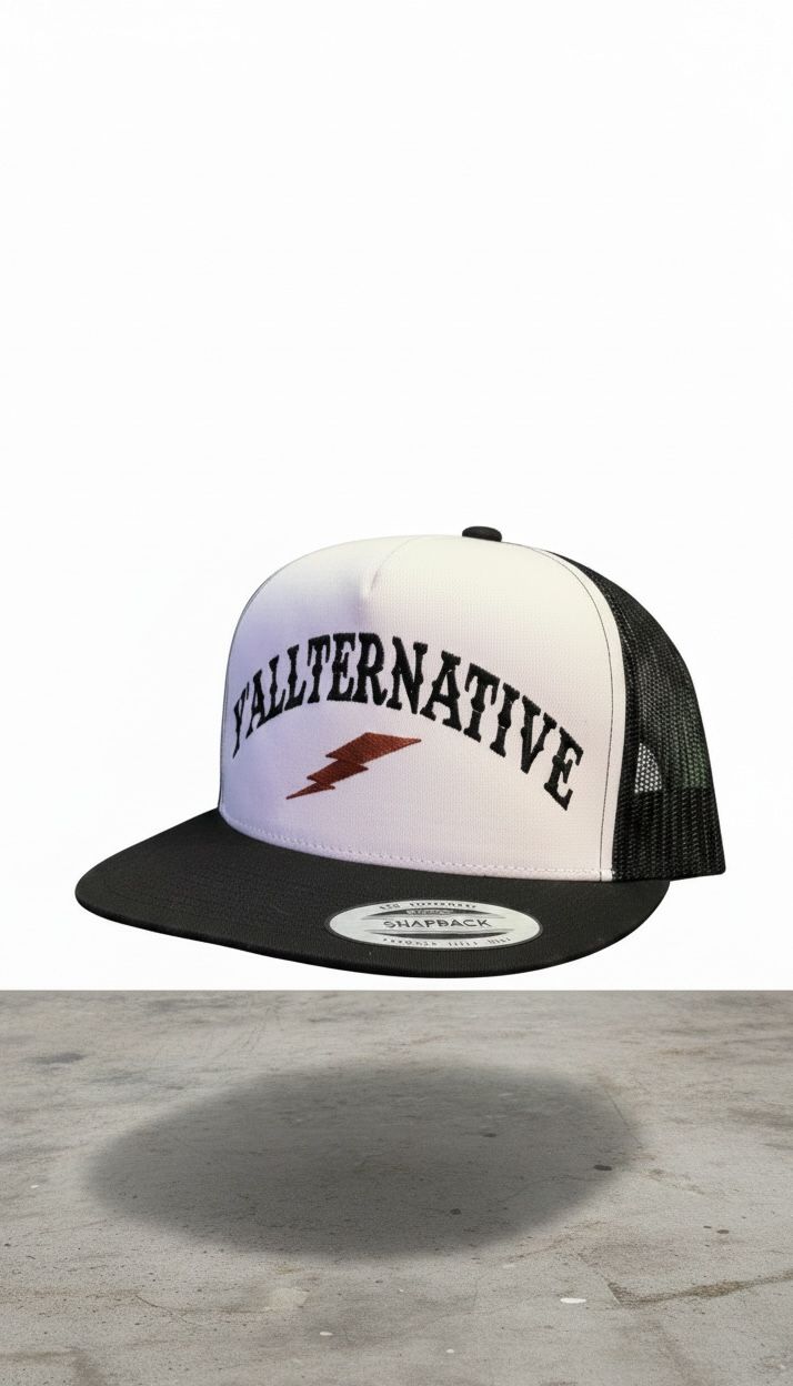 White and black snapback hat with 'YALLTERNATIVE' text and lightning bolt on a concrete and white background